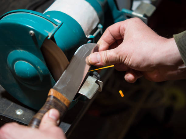istock Knife sharpener and a hand with a blade, a man sharpens a knife on a grinder 1397506656