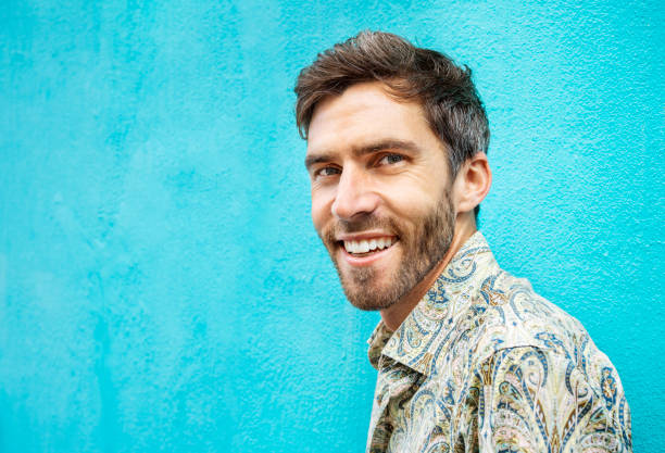 istock Stylish young man smiling against a blue wall outside 1397506684