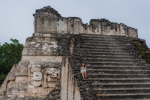 Young Caucasian woman sitting on stairs in  Tikal National Park