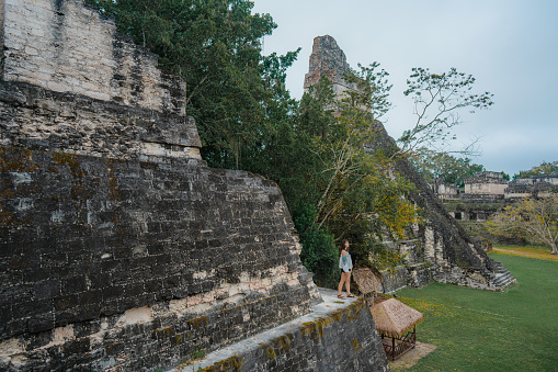 Young Caucasian woman standing on stairs of pyramid in  Tikal National Park