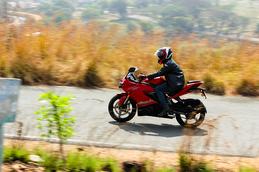 A Motion blur picture of a speeding superbike and the rider travelling through the woods on a hill range near Mysore, India.