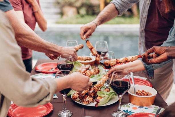 hands grabbing skewers from the table with wine glasses at the poolside summer barbecue party hands grabbing skewers from the table with wine glasses at the poolside summer barbecue party aperitif stock pictures, royalty-free photos & images