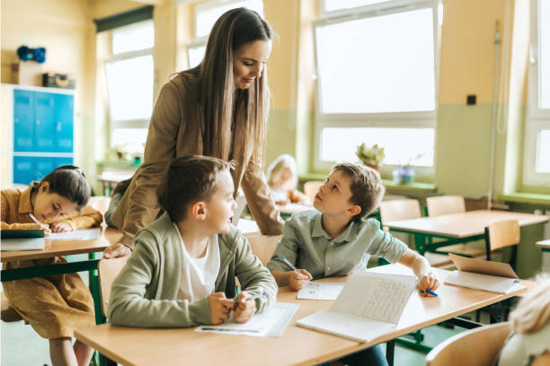 istock young female teacher explaining to schoolboys at desk in lesson 1397508743