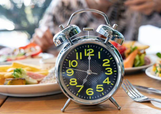 How to Use Intermittent Fasting to Improve Mood and Focus 1 alarm clock intermittent fasting eight hour feeding window concept and eating a healthy food
