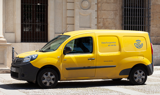 Seville, Spain - 7th April 2022 A yellow Spanish electric post van with the 2019 rebranded logo. It has the words 