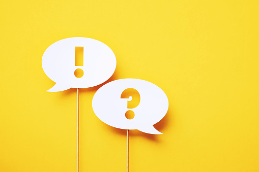 Exclamation point and question mark written circular white chat bubble pair sitting on yellow background. Horizontal composition with copy space.