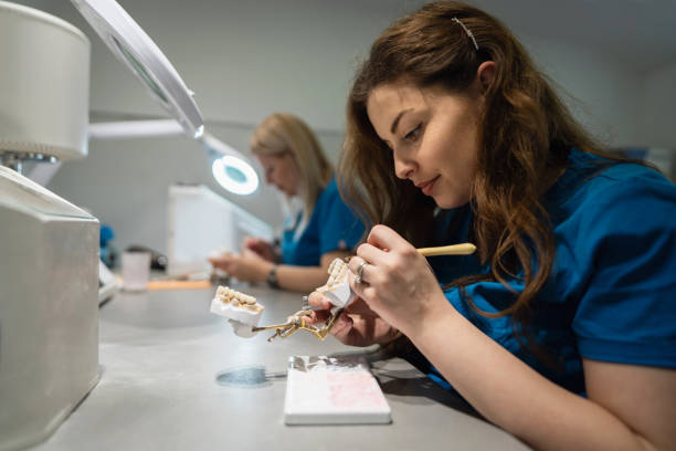 tecnici donne, presso il laboratorio odontotecnico, che realizzano protesi dentarie - scrub brush immagine foto e immagini stock