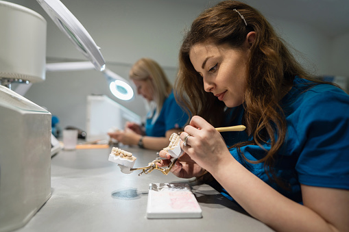 Caucasian female technicians, at the dental laboratory, making dentures