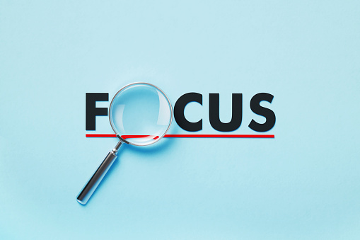 Magnifier forming focus word on blue background. Horizontal composition with copy space. Analysis concept.