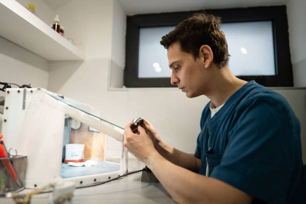 tecnico maschio, presso il laboratorio odontotecnico, macinando le protesi con trapano - dental hygiene laboratory dental equipment technician foto e immagini stock