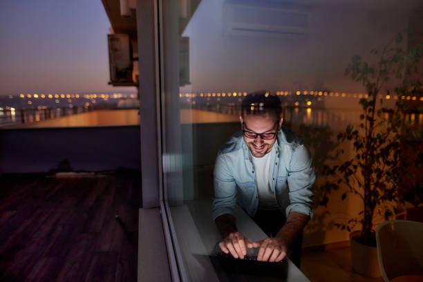 istock Happy man using laptop by the window at night. 1397511858