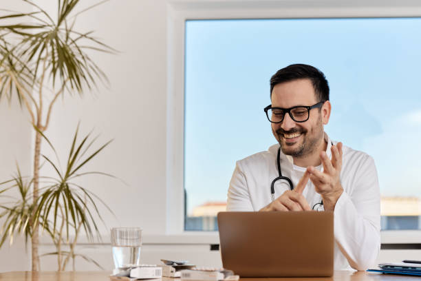 istock Happy doctor having a video call over laptop at his office. 1397512100