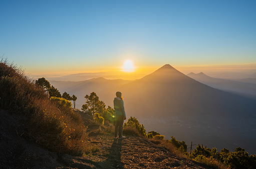 Young Caucasian woman standing on the background of  volcano in Guatemala