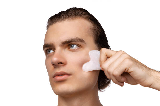 istock Young attractive man with perfect smooth skin, applying face massagers isolated over white studio background. Cosmetics, health care, skin care, beauty 1397515326