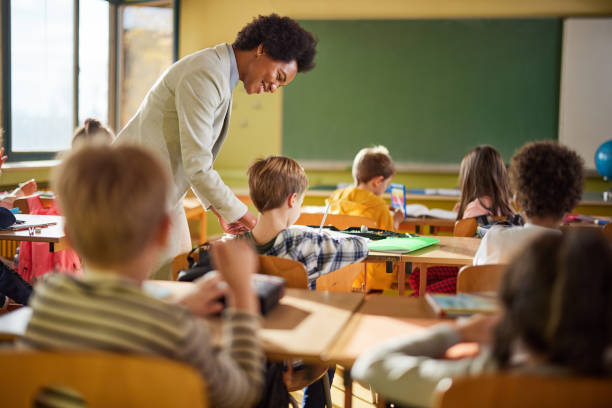 istock Happy black professor assisting schoolboy on a class at school. 1397516058