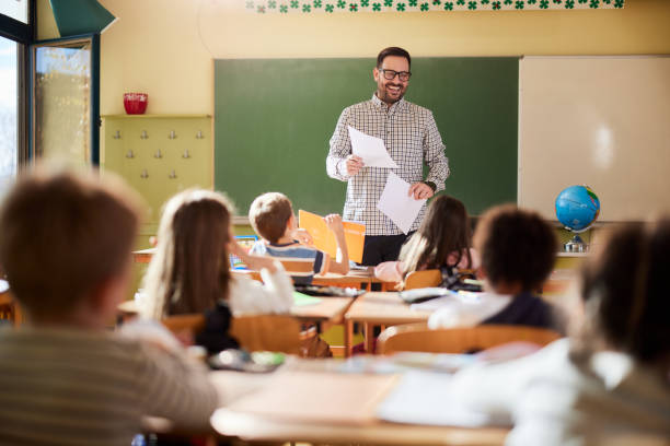 istock Happy male teacher giving a lecture at elementary school. 1397516134