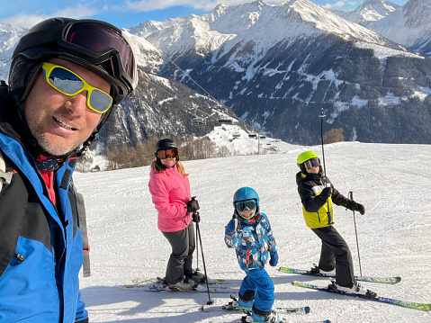 Portrait of family skiing in ski slope against mountain.