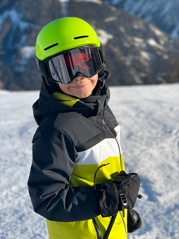 Portrait of boy standing and smiling in ski slope mountain.