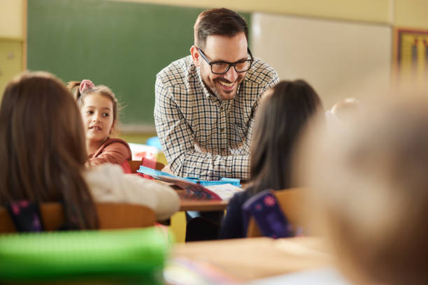 istock Happy professor assisting his elementary students on a class at school. 1397516994