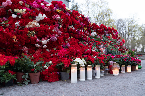 Huge pile of red flowers and candles.