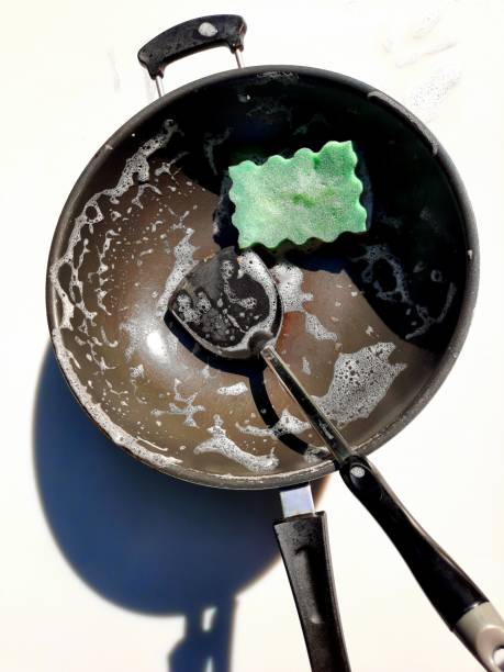 Cleaning Cooking pan and ladle after food preparation.