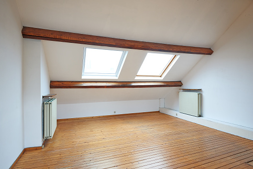 Interior attic windows and hardwood floor in empty room