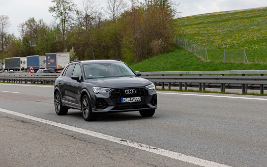 Kempten, Allgäu, Schwaben, Bavaria, Germany, may 1st 2022, a black German Audi Q3 Sportback approaching on the German A7 Autobahn at Kempten - in the background on the other side of the road is a parking lot with some trucks - with a length of 963 km between the borders of Denmark in the north and Austria in the south, the Autobahn 7 is the longest Autobahn in Germany