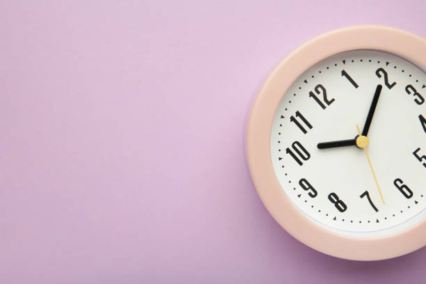 istock Pink clock on purple background. Top view. 1397523778
