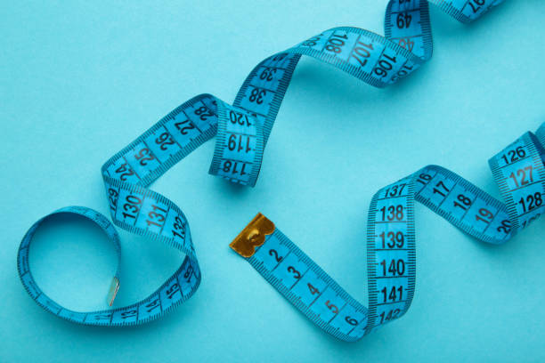 istock Blue plastic measure tape with metric scale over on color blue background. 1397524419