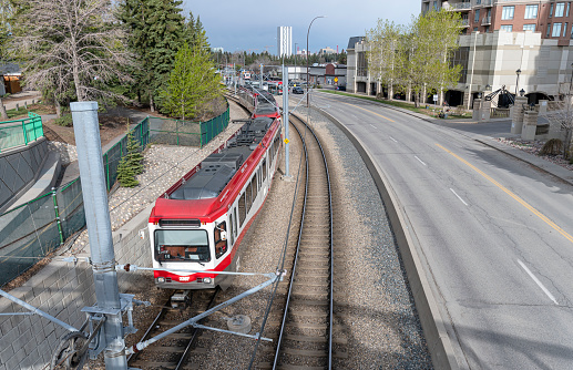 Calgary, Alberta, Canada – May 13, 2022:  An aerial view of a light rail transit train (C-Train) leaving the North Hill Station