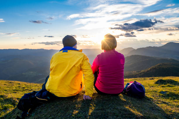 istock People sitting on grass and looking at setting sun 1397527240