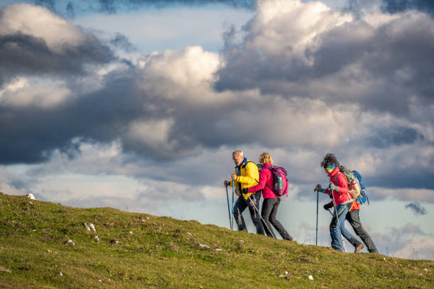 istock Hikers climbing uphill on grass slope, dramatic clouds in sky in background 1397527250