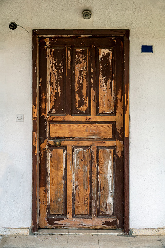 Old and worn brown wooden street door.