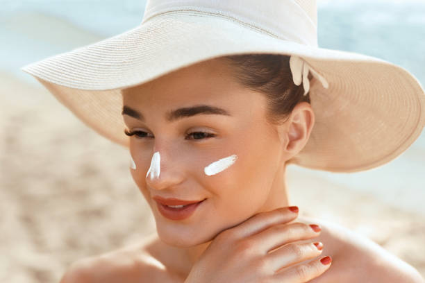 Suncream. Suntan Lotion Beautiful Woman Applying on beautiful on Face. Sunscreen Solar Cream. Skin care. Sun protection.The Girl Uses  Moisturizer Sunblock stock photo