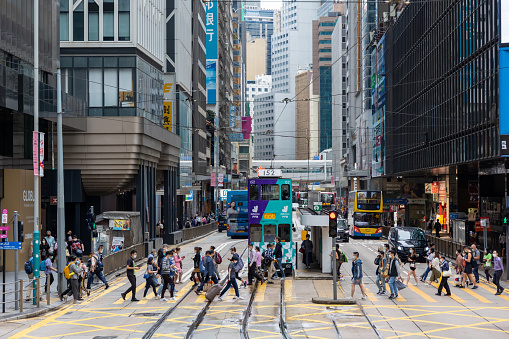 Hong Kong - May 16, 2022 : Pedestrians walk past the Des Voeux Road Central in Central, Hong Kong. Des Voeux Road Central was named after the 10th Governor of Hong Kong, Sir William Des Vœux.