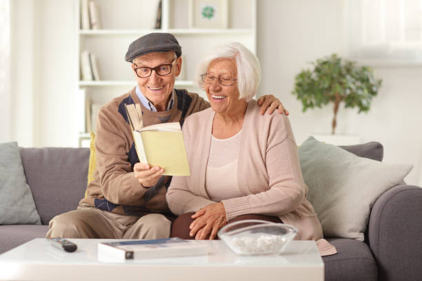 istock Happy elderly couple sitting on a sofa at home and reading a book 1397538225