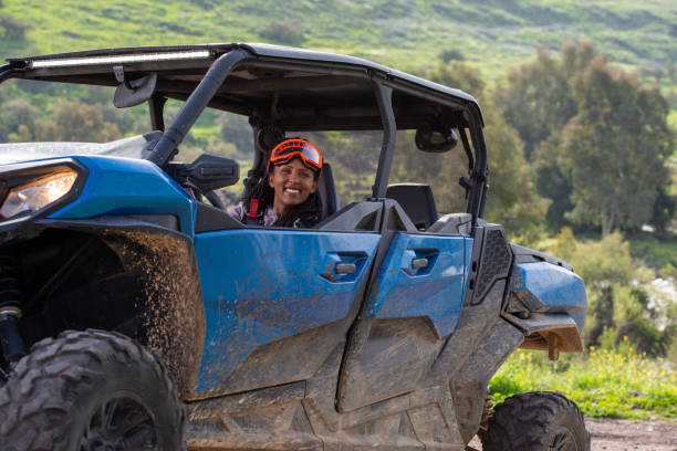 A woman driving a side-by-side, off-road recreation vehicle. Outdoor pursuit, hobby, and leisure activity. Extreme sportswoman driver enjoying and having fun while riding on an off-road vehicle. The woman wearing UTV Powersports goggles. An extreme, adrenaline-pumping adventure on the terrain, riding tour on a 4x4, Side-by-Side, UTV vehicle. Outdoor recreation activities. Off-Road Experience. quadbike stock pictures, royalty-free photos & images