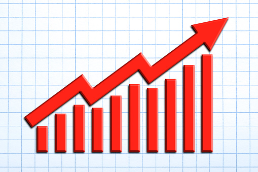 A red arrow and a bar chart showing positive growth on a sheet of graph paper.