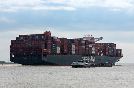 Stade, Germany – May 11, 2022: Ultra-large container ship AL NEFUD,  operated by Hapag-Lloyd,  on Elbe river heading to Hamburg, bulk carrier SCHÖNRAIN passing by.