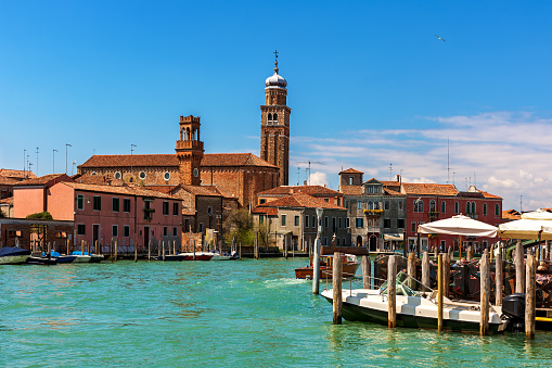 Canal and old historic buildings , towers and belfries on the island of Murano on Venetian lagoon in Italy.