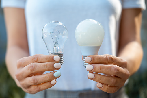 Woman holding classic light bulb and new LED light bulb. Power saving concept.