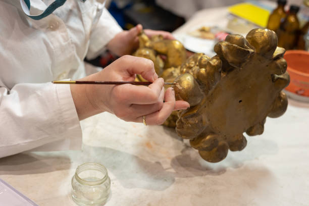 istock Experienced Lady Restoring a Small Gilded Statuette with a very Fine Brush in Her Art Studio 1397544644