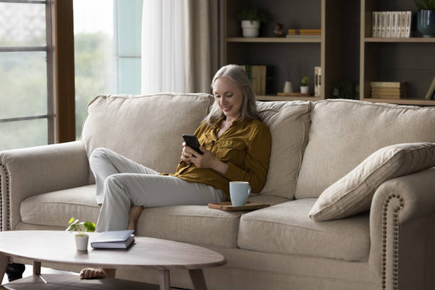 istock Cheerful grey haired lady using mobile phone at home 1397545850