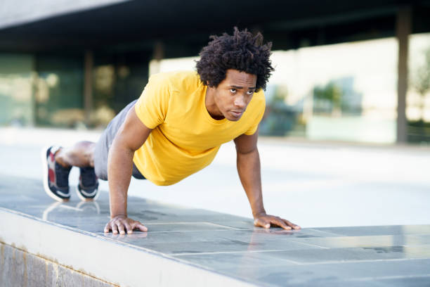 istock Black man doing triceps dip exercise on city street bench. 1397547509