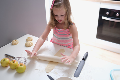 Child girl with rolling pin for baking cookies for dough. Children cooking concept