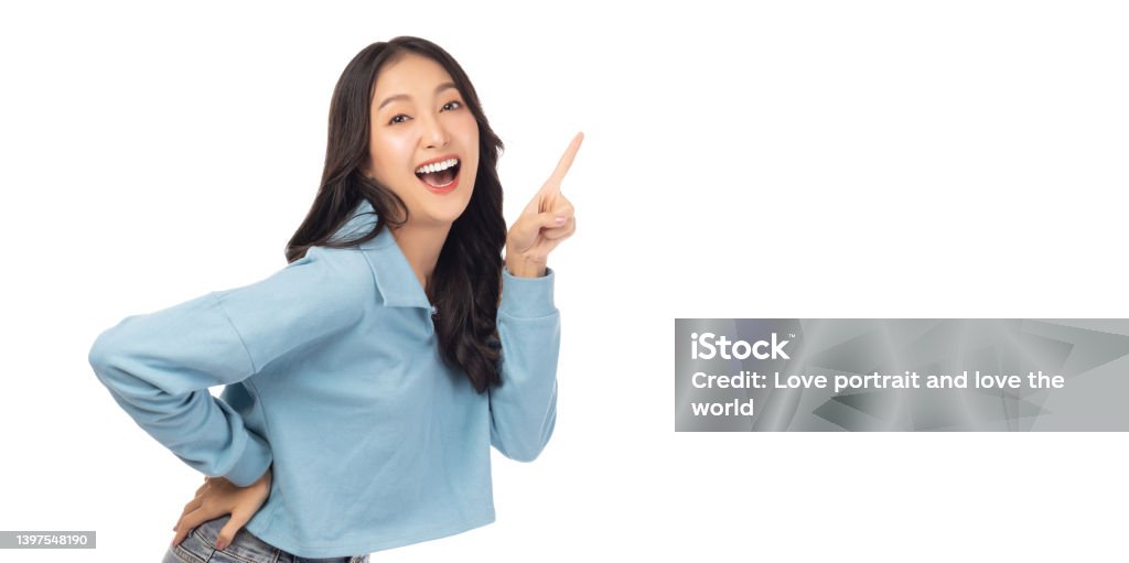 Beautiful young Asian woman pointing up to copy space and looking at camera with smile face and happy Pretty girl act like a satisfied product, use for advertising with isolated on white background White Background Stock Photo