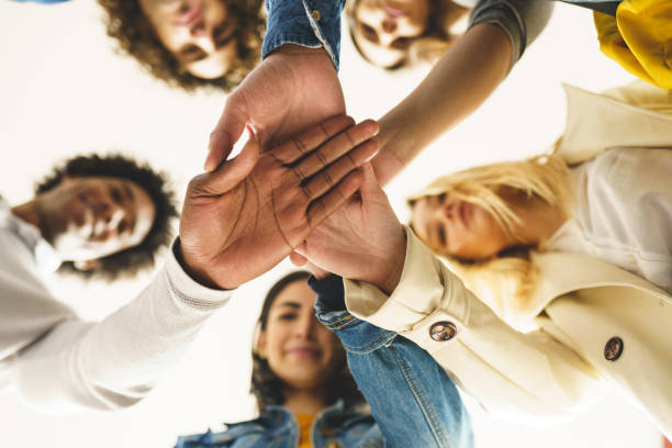 Diverse people stacking hands together From below of group of content multiracial friends joining hands together and standing in circle hands clasped stock pictures, royalty-free photos & images