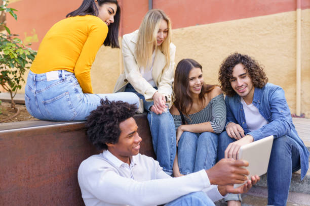 ethnische gruppe junger menschen, die ein digitales tablet im freien im urbanen hintergrund betrachten. - computer student mixed race person multi ethnic group stock-fotos und bilder