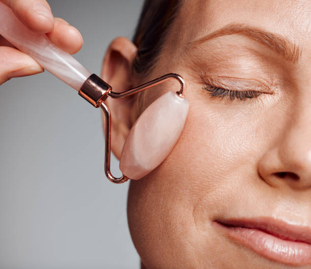 istock Beautiful mature woman posing with face roller in studio against a grey background 1397549120