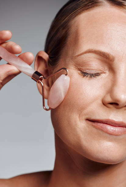 istock Beautiful mature woman posing with face roller in studio against a grey background 1397549129